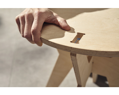 Person hält einen Holzhocker aus Schichtholz.