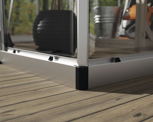 Detailaufnahme eines Gewächshauses mit Aluminiumrahmen und Verglasung, stehend auf einem Holzboden