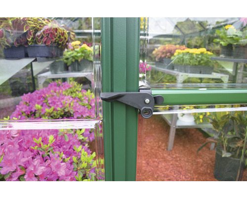 Detailansicht eines Gewächshauses mit Türgriff und Pflanzen im Inneren
