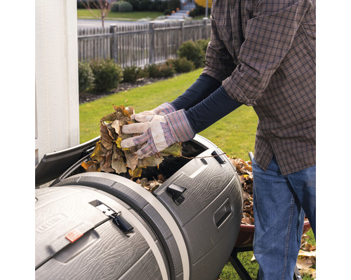 Eine Person befüllt einen Kompostbehälter mit Laub