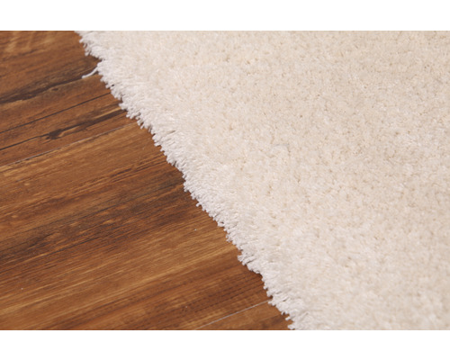 Detailansicht eines hellen Teppichs auf Holzboden