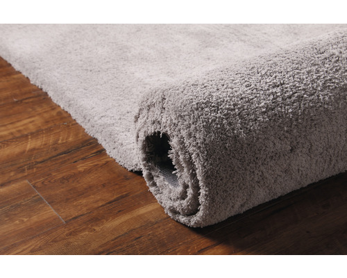 Grauer Teppich auf Holzboden, teilweise aufgerollt
