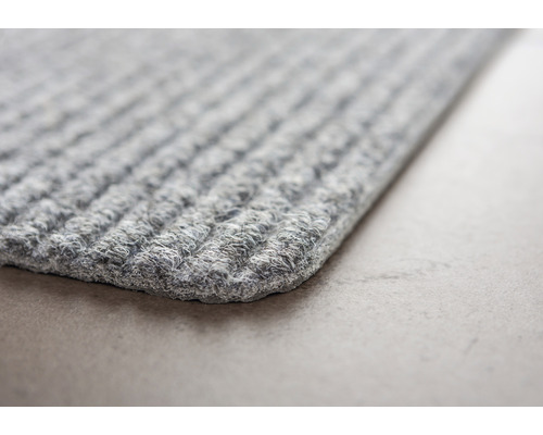 Detailansicht einer grauen Fußmatte mit Rippenstruktur.