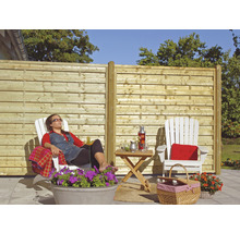 Szene im Garten mit Holzzaun, Gartenmöbeln und entspannter Person