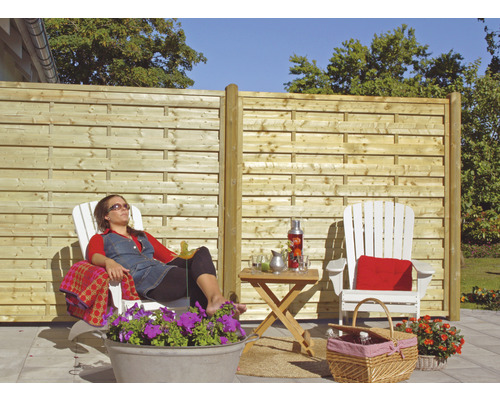 Scène de jardin avec clôture en bois, mobilier de jardin et personne se détendant