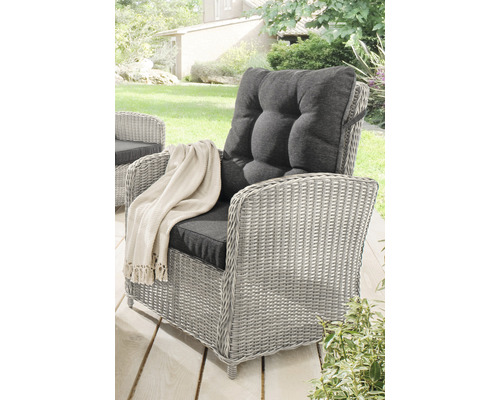 Fauteuil en rotin gris avec coussins gris et couverture dans le jardin