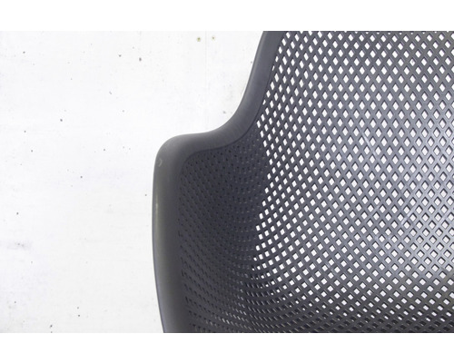 Gros plan d''une chaise noire avec accoudoir et assise perforée.