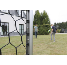 Detailansicht eines Fußballtors mit Netz und zwei spielenden Personen im Hintergrund