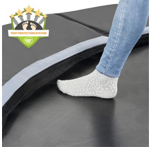 Gros plan d''un trampoline avec système de protection des pieds et une personne debout dessus avec des chaussettes.
