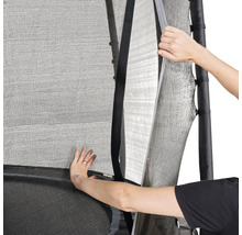 Gros plan d''un filet de sécurité de trampoline partiellement ouvert par deux mains pour dégager l''entrée