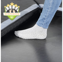 Detailaufnahme eines Trampolins mit Fußschutzsystem und Fuß einer Person mit Socken