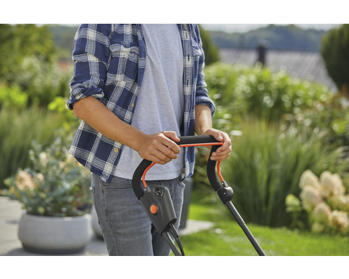 Eine Person bedient einen Rasenmäher im Garten.