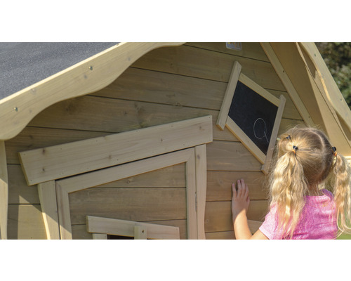Gros plan d''une cabane de jeu en bois pour enfants avec un tableau noir sur lequel une fillette dessine.