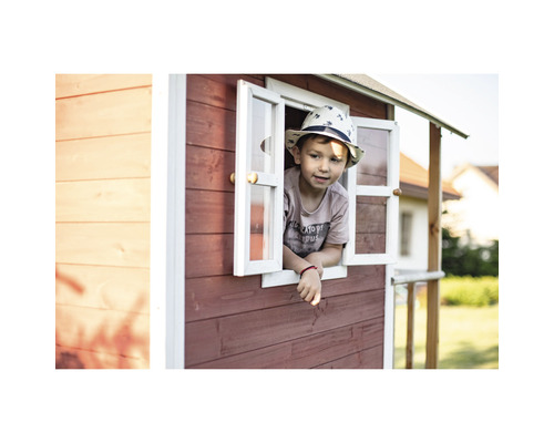Kind schaut aus dem Fenster eines Spielhauses aus Holz