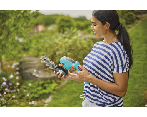 Frau hält eine Gardena Akku Grasschere mit wechselbaren Messern in der Hand.