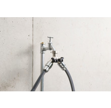 Robinet avec deux raccords et raccords de tuyau devant un mur en béton