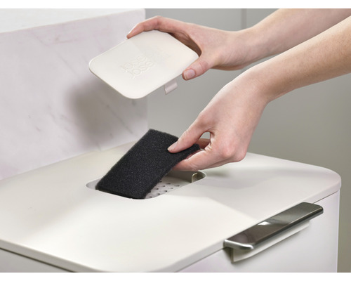 Une personne place un filtre dans une poubelle.