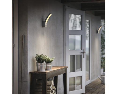 Scène avec deux appliques murales extérieures, table en bois, plantes et porte