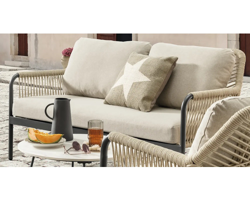 Terrassenmöbel-Set mit Sofa, Sessel und Tisch mit Getränken und Snacks für eine entspannte Atmosphäre im Freien.