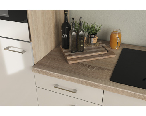 Scène de cuisine avec plan de travail, bouteilles, herbes aromatiques et plaque de cuisson