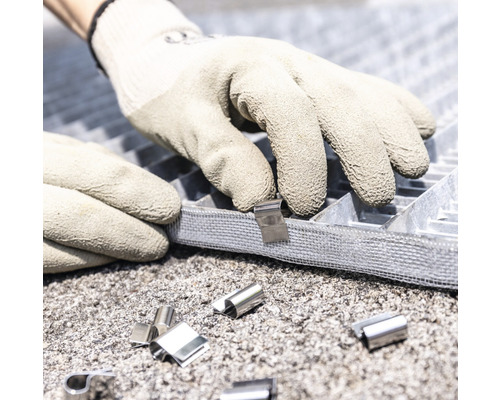 Person befestigt eine Rasenwabenmatte mit Befestigungsclips