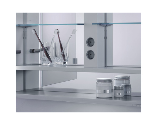 Scène de salle de bains avec armoire de toilette, gobelets pour brosses à dents, brosses à dents, prises électriques et pots de cosmétiques