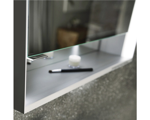 Detailaufnahme eines Spiegelschranks mit Ablage und Kosmetikartikeln