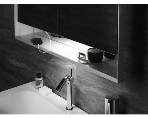 Badezimmer mit Waschbecken, Armatur, Spiegelschrank, Handy und Pflegeprodukten