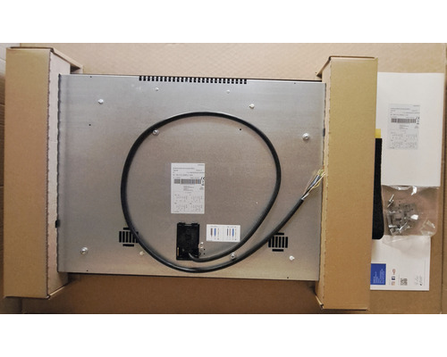 Vue arrière d''une plaque de cuisson avec câble de raccordement et accessoires de montage dans un emballage