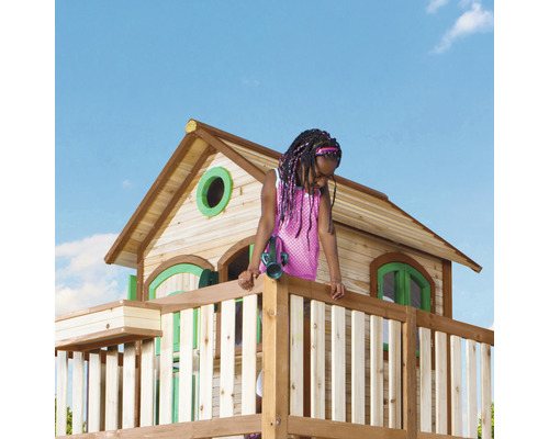 Mädchen auf einem Holzspielturm mit Haus