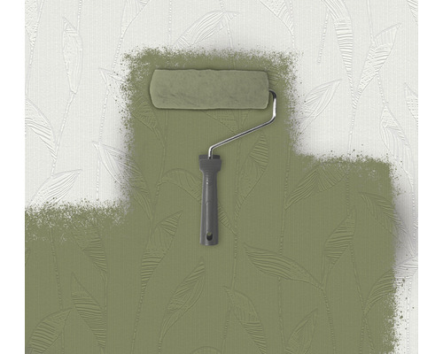 Farbroller streicht grüne Farbe auf eine Wand mit Blattmuster.