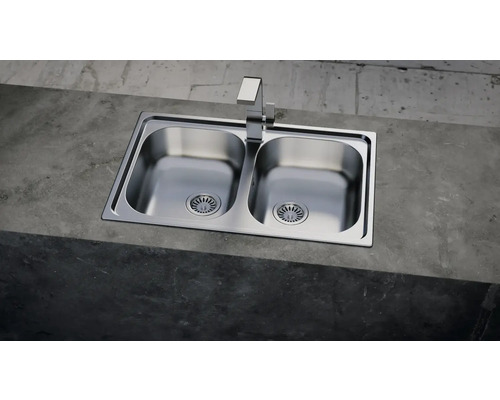 Doppelspülbecken aus Edelstahl mit Wasserhahn auf einer Betonoberfläche