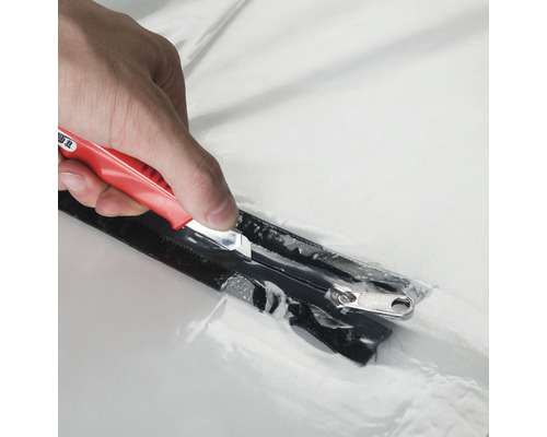 Gros plan sur un couteau coupant une fermeture éclair