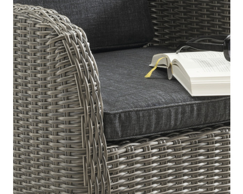 Detailaufnahme eines Rattansessels mit Kissen und Buch