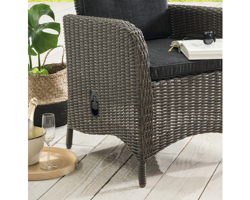 Nahaufnahme eines Korbsessels mit Kissen, Buch, Sonnenbrille und Getränken.