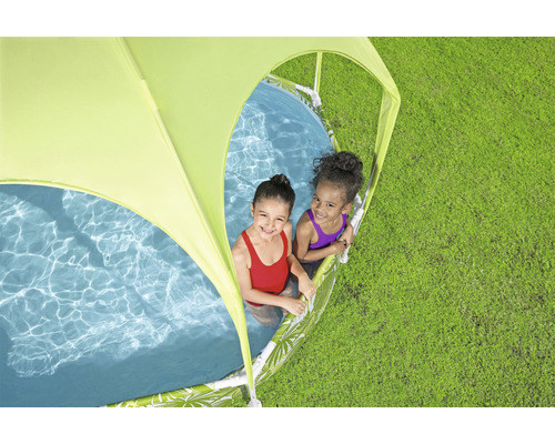 Zwei Kinder spielen in einem Planschbecken mit Sonnenschutz auf einer Wiese.