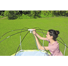 Eine Frau baut ein Planschbecken mit Sonnenschutz im Garten auf.