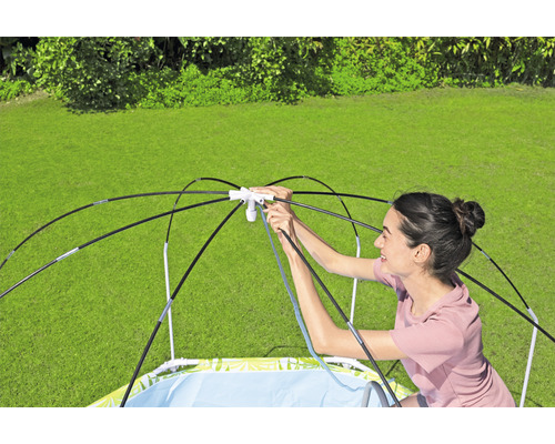 Eine Frau baut ein Planschbecken mit Sonnenschutz im Garten auf.