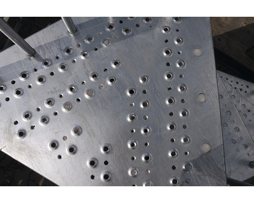 Detailaufnahme einer Treppenstufe aus Metall mit Löchern