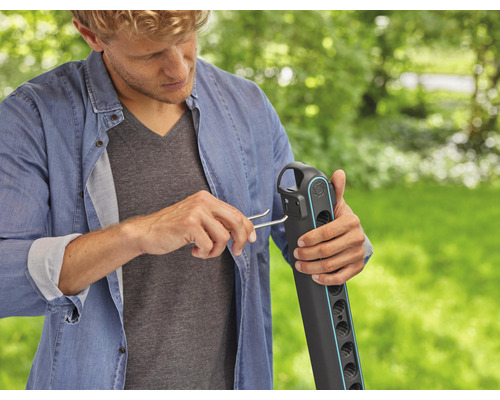 Un homme monte une douche de jardin à l''extérieur.