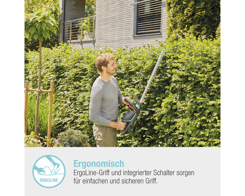 Ein Mann schneidet eine Hecke mit einer Heckenschere.