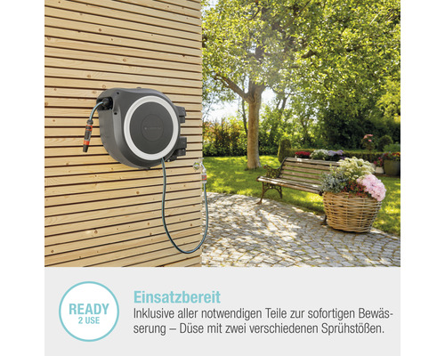 Gartenschlauchbox an Holzwand mit Garten im Hintergrund