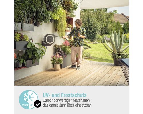 Mann bewässert Pflanzen mit einer Schlauchbox auf einer Terrasse