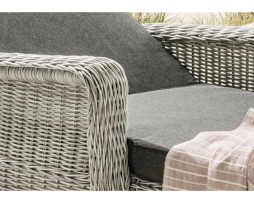 Detailansicht eines Korbsessels mit grauem Sitzkissen und einer gestreiften Decke