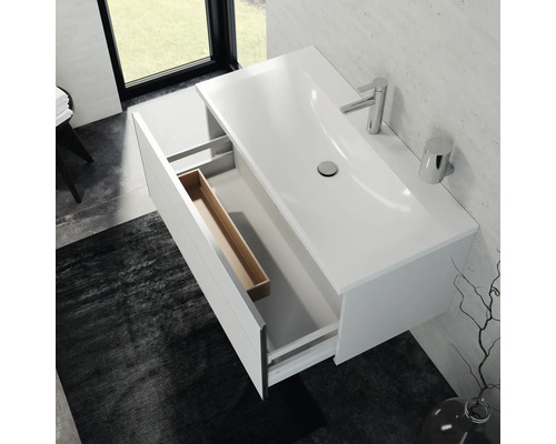 Meuble sous-vasque avec tiroir ouvert, vasque à poser, robinetterie et accessoires de salle de bains dans une salle de bains claire.