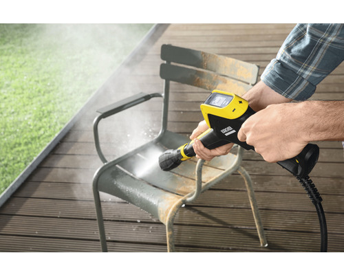 Une personne nettoie une chaise de jardin avec un nettoyeur haute pression Kärcher.