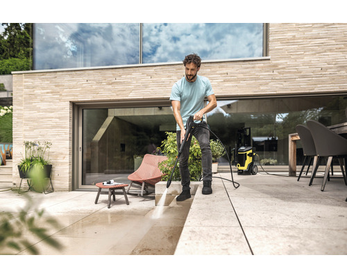 Mann reinigt Terrasse mit Hochdruckreiniger