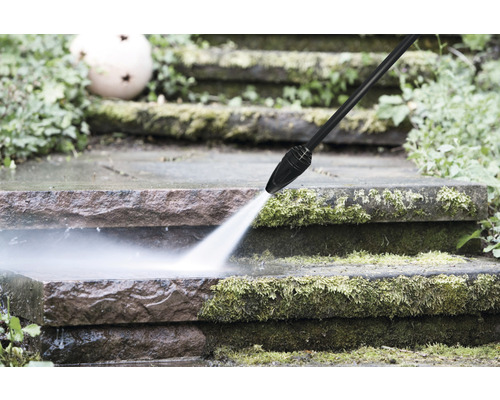 Ein Hochdruckreiniger reinigt eine Steintreppe von Moos.