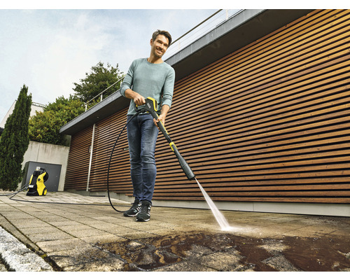 Mann reinigt Terrasse mit Hochdruckreiniger