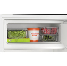 Compartiment congélateur avec petits pois, glace à la framboise, framboises et haricots verts dans des conteneurs de stockage